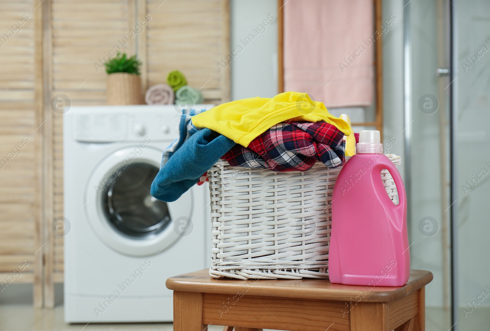 Photo of Wicker basket with laundry and detergent in bathroom