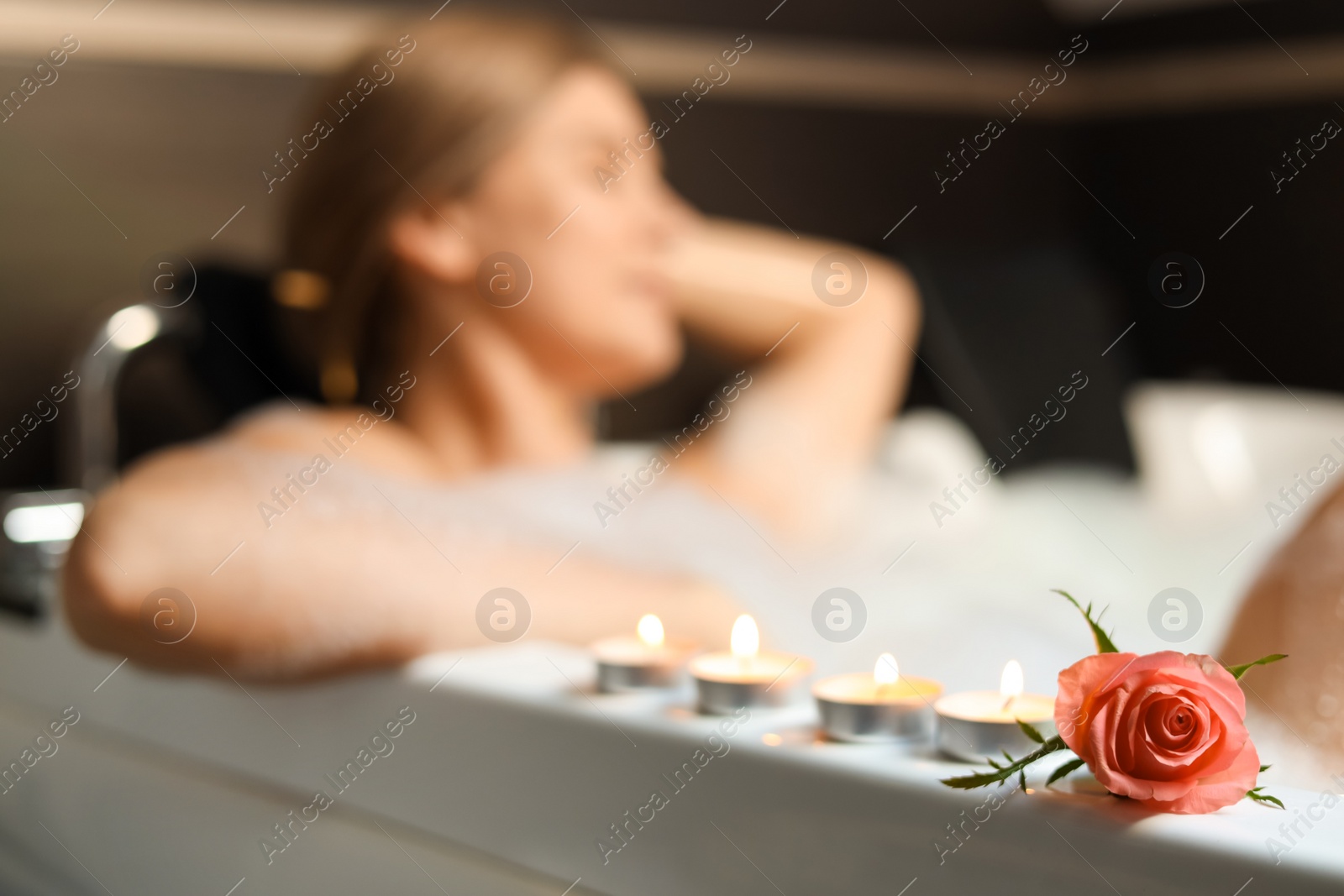 Photo of Woman taking bubble bath indoors, focus on flower. Romantic atmosphere