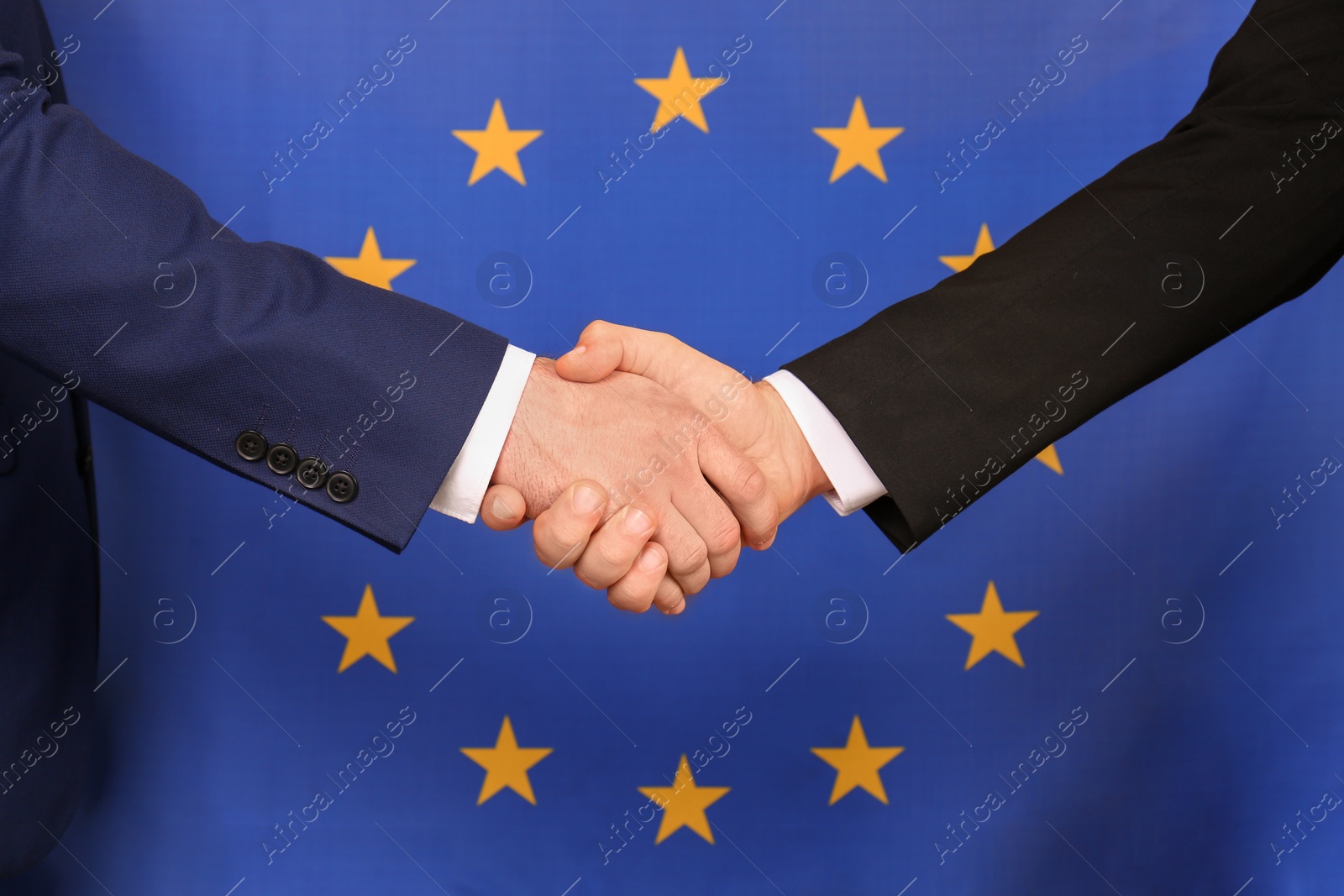 Photo of Men shaking hands against flag of European Union, closeup. International relationships