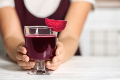 Woman with glass of beet smoothie at table, closeup