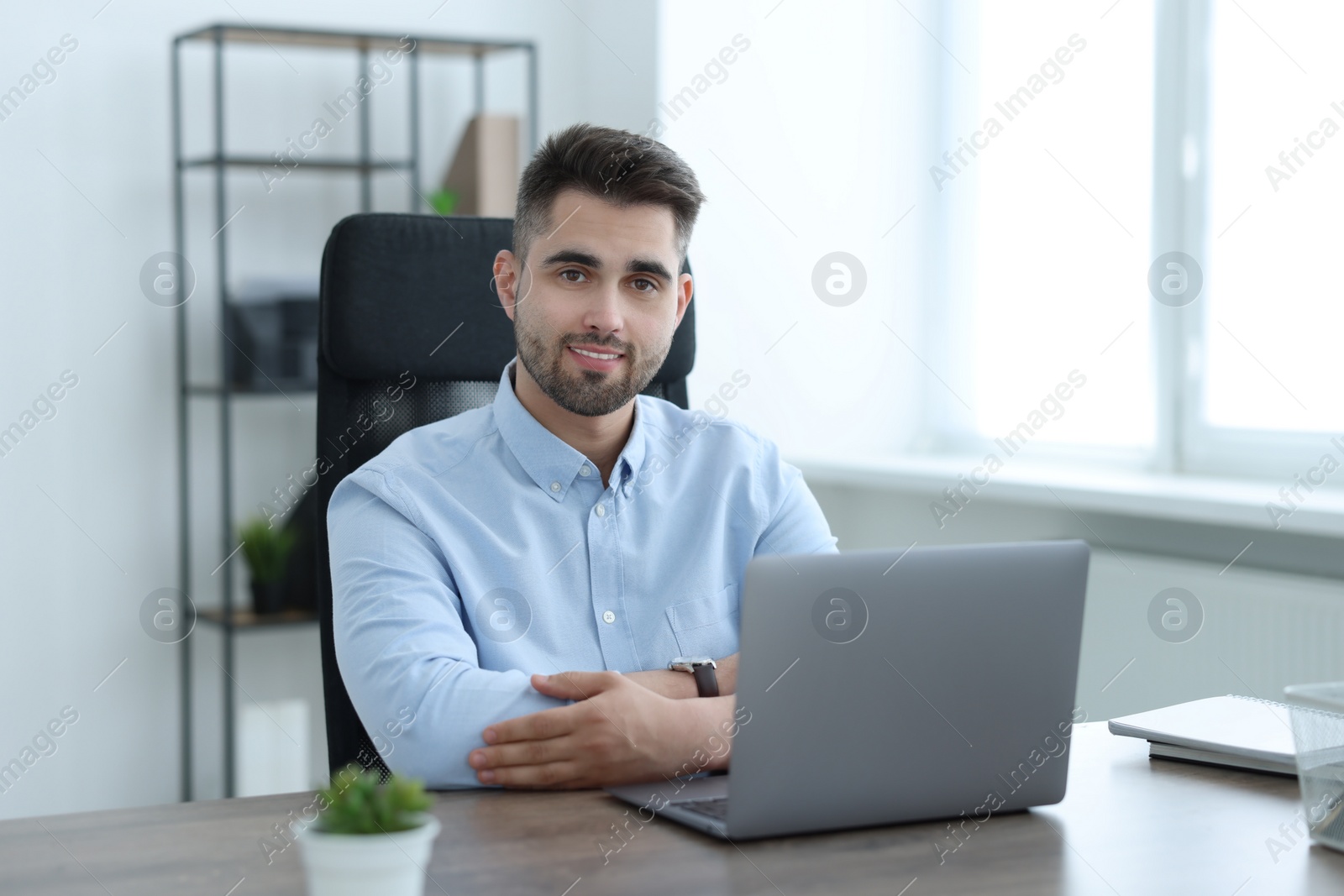 Photo of Happy young programmer working with laptop in office