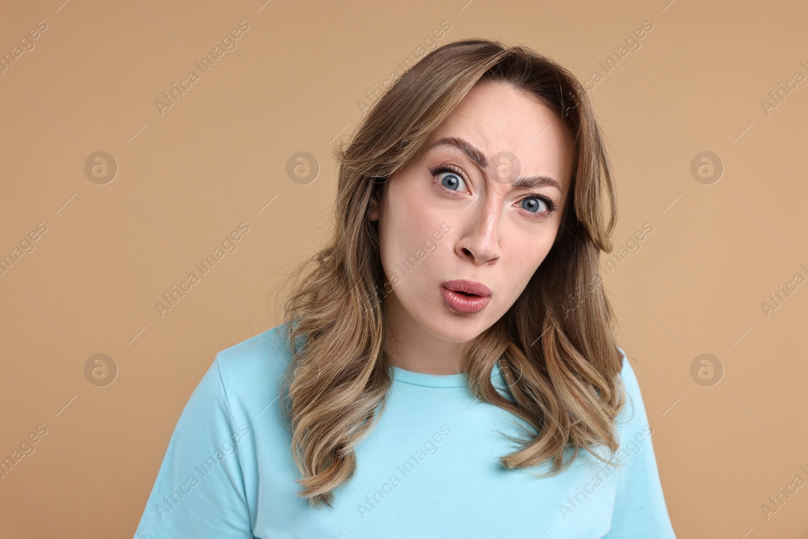 Photo of Portrait of surprised woman on beige background