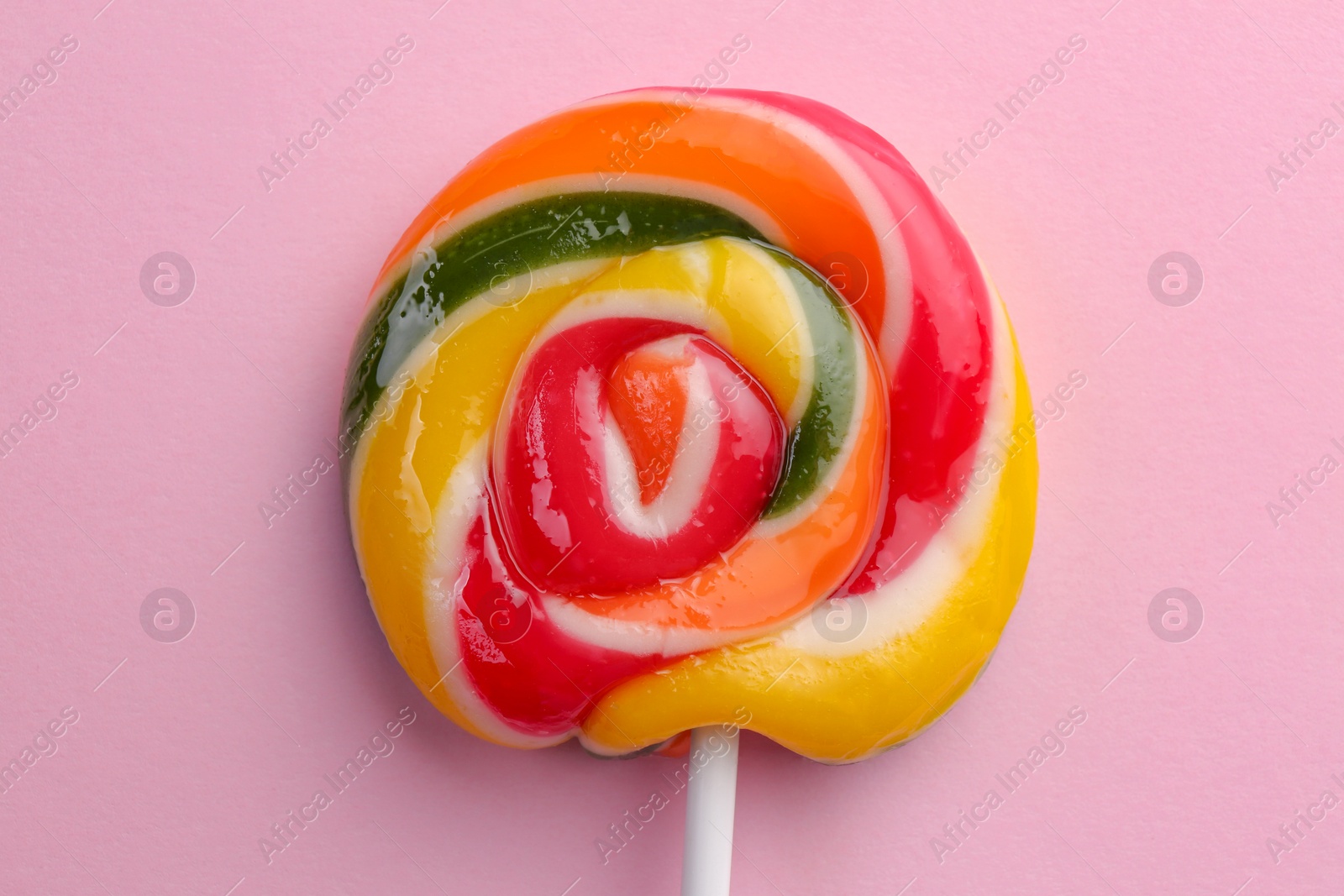 Photo of Sweet colorful lollipop on pink background, top view