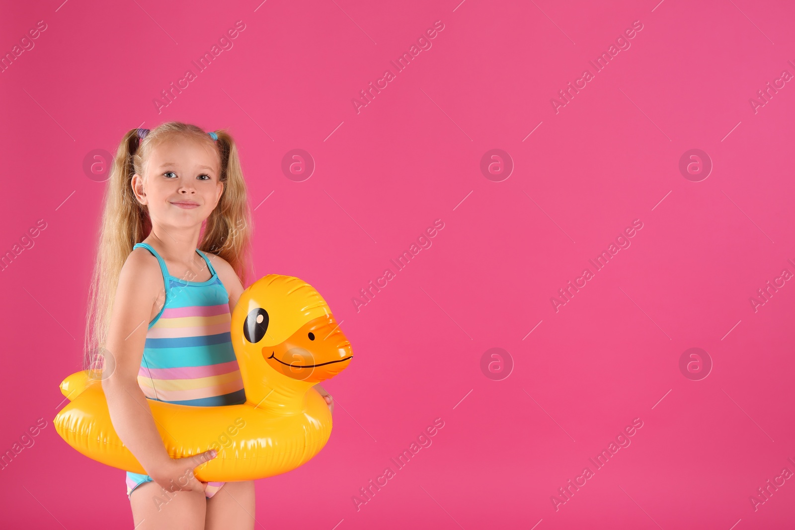 Photo of Cute little child in beachwear with bright inflatable ring on pink background. Space for text