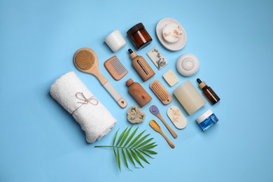 Photo of Flat lay composition with different spa products and tropical leaf on light blue background