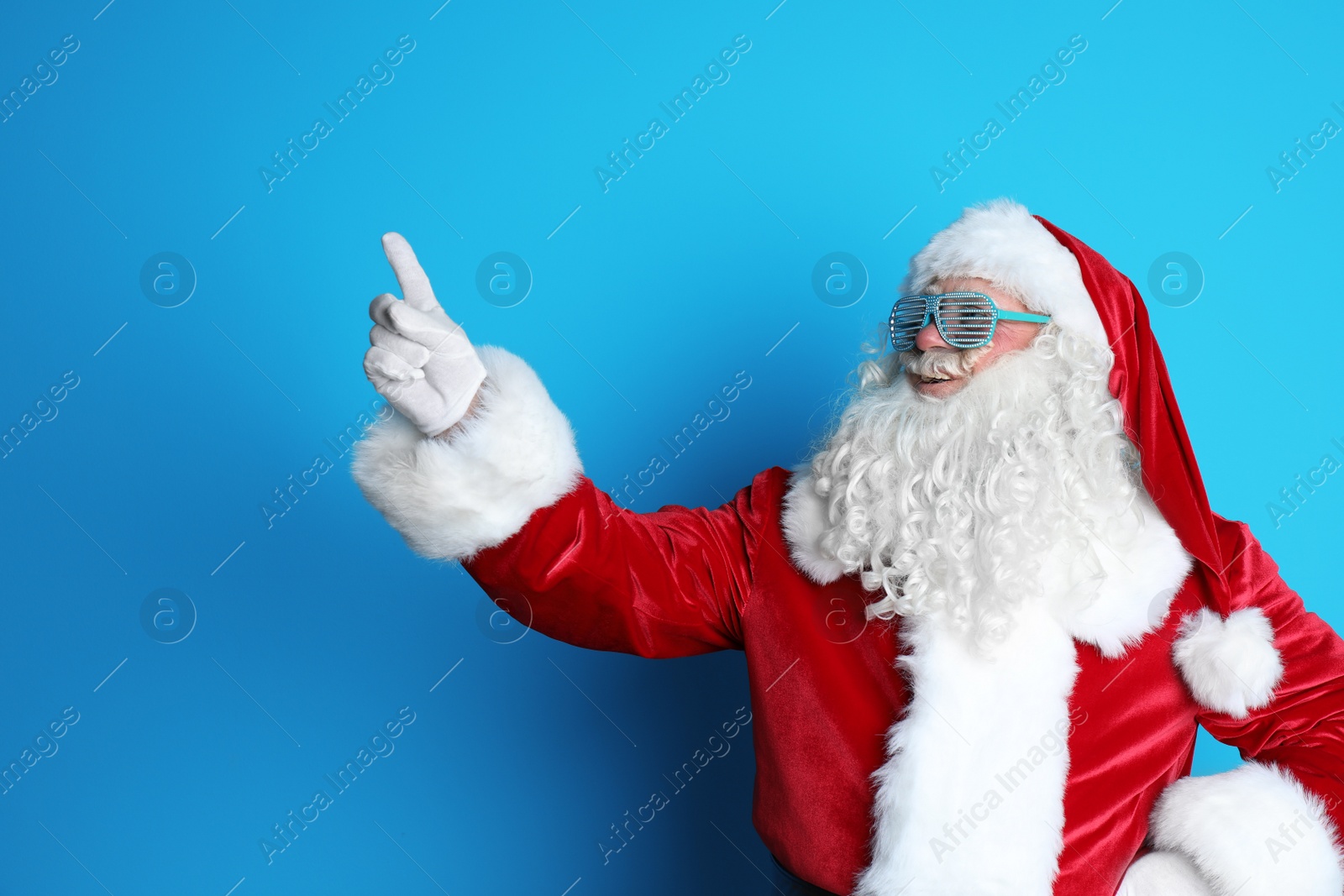 Photo of Authentic Santa Claus wearing funny glasses on color background