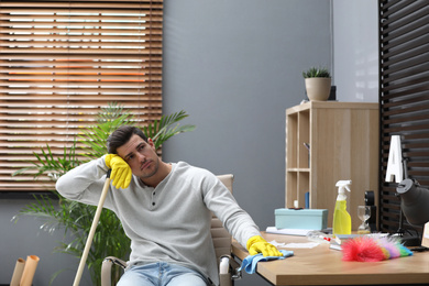 Photo of Lazy man procrastinating while cleaning at home