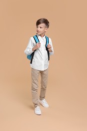Photo of Back to school. Cute boy with backpack on beige background