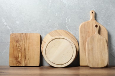 Photo of Different wooden cutting boards on table near gray wall