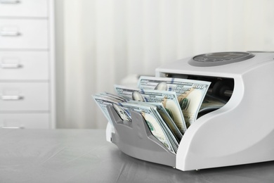 Photo of Modern bill counter with money on table indoors. Space for text