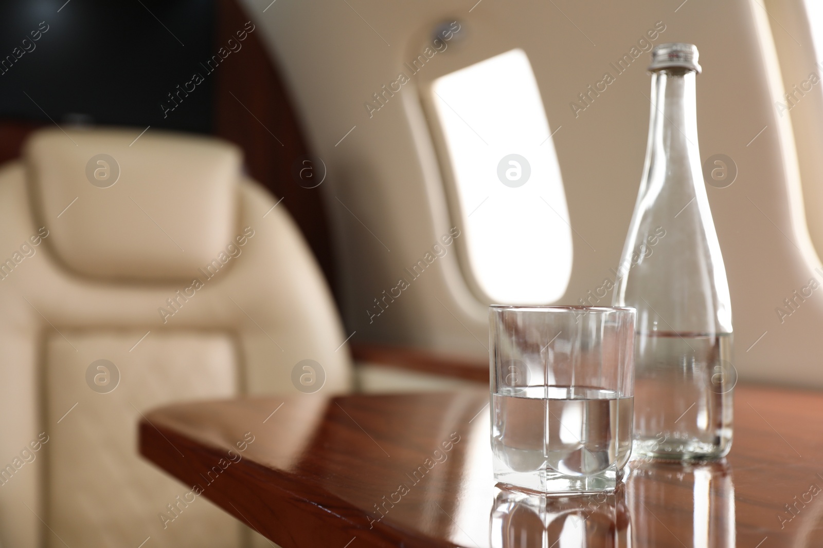 Image of Glass and bottle with water on plane. Comfortable flight