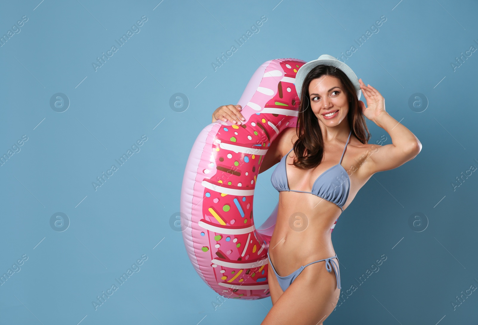 Photo of Beautiful woman in stylish bikini with inflatable ring on blue background. Space for text