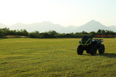 Modern quad bike in field on sunny day, space for text