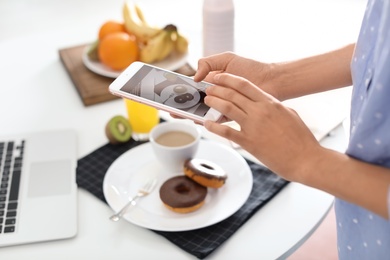 Photo of Food blogger taking photo of breakfast at home, focus on phone display