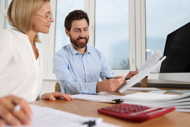 Photo of Happy businesspeople working with documents at wooden table in office