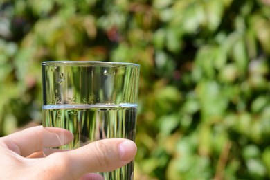 Photo of Woman holding glass of water outdoors, closeup. Space for text