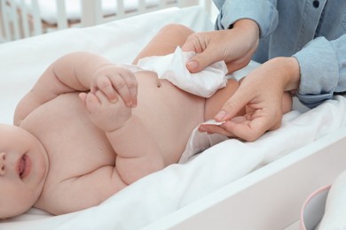 Mother changing baby's diaper on table at home, closeup