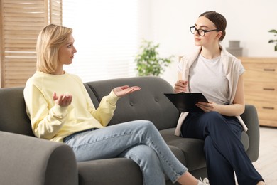 Photo of Professional psychotherapist working with on sofa patient in office