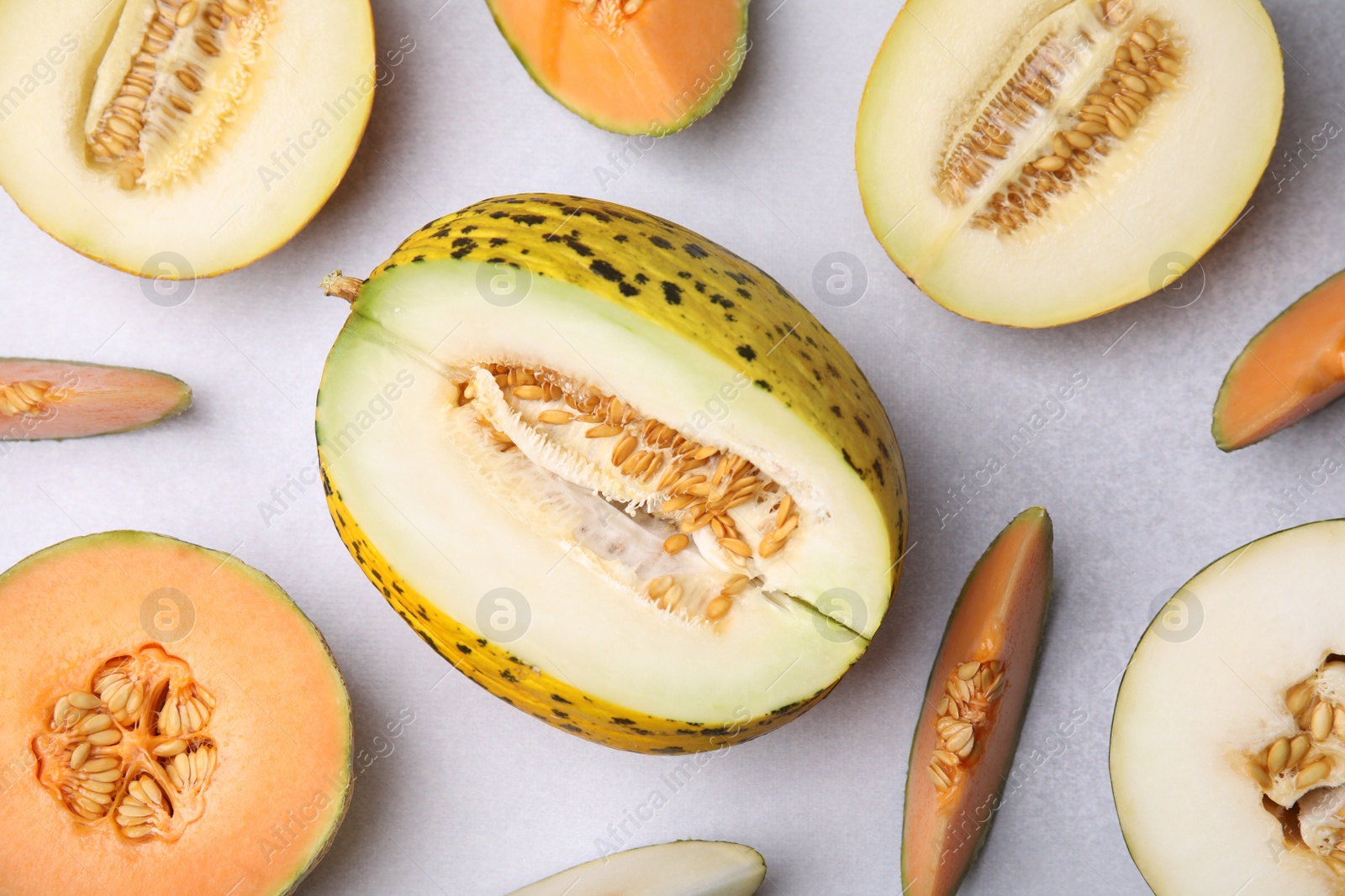 Photo of Tasty colorful ripe melons on light grey table, flat lay