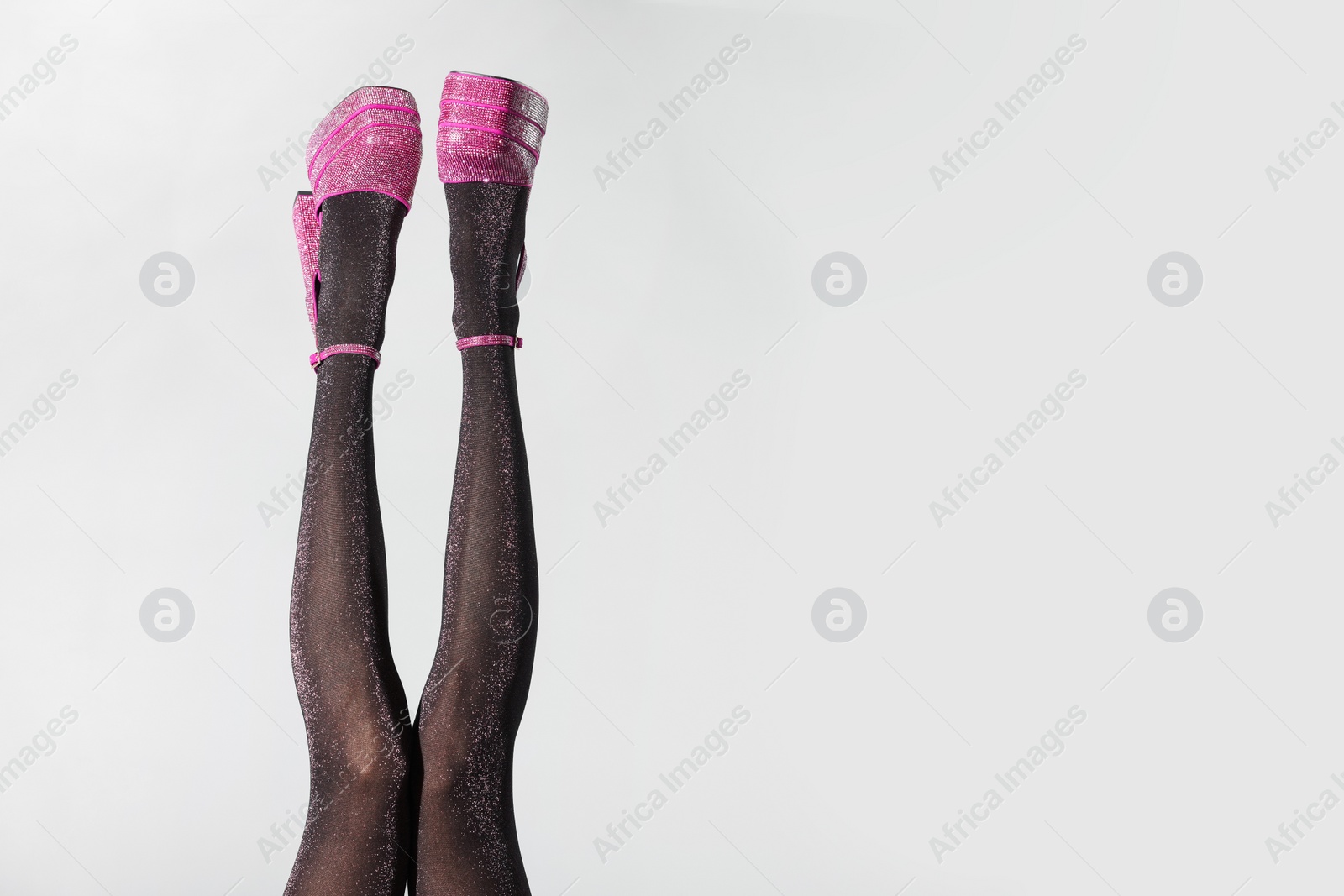 Photo of Woman wearing pink high heeled shoes with platform and square toes on light grey background, closeup. Space for text