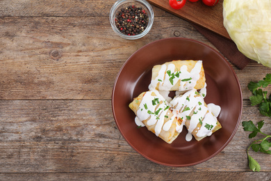 Photo of Delicious cabbage rolls served on wooden table, flat lay. Space for text