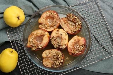 Photo of Tasty baked quinces with walnuts and honey in bowl on black table, flat lay