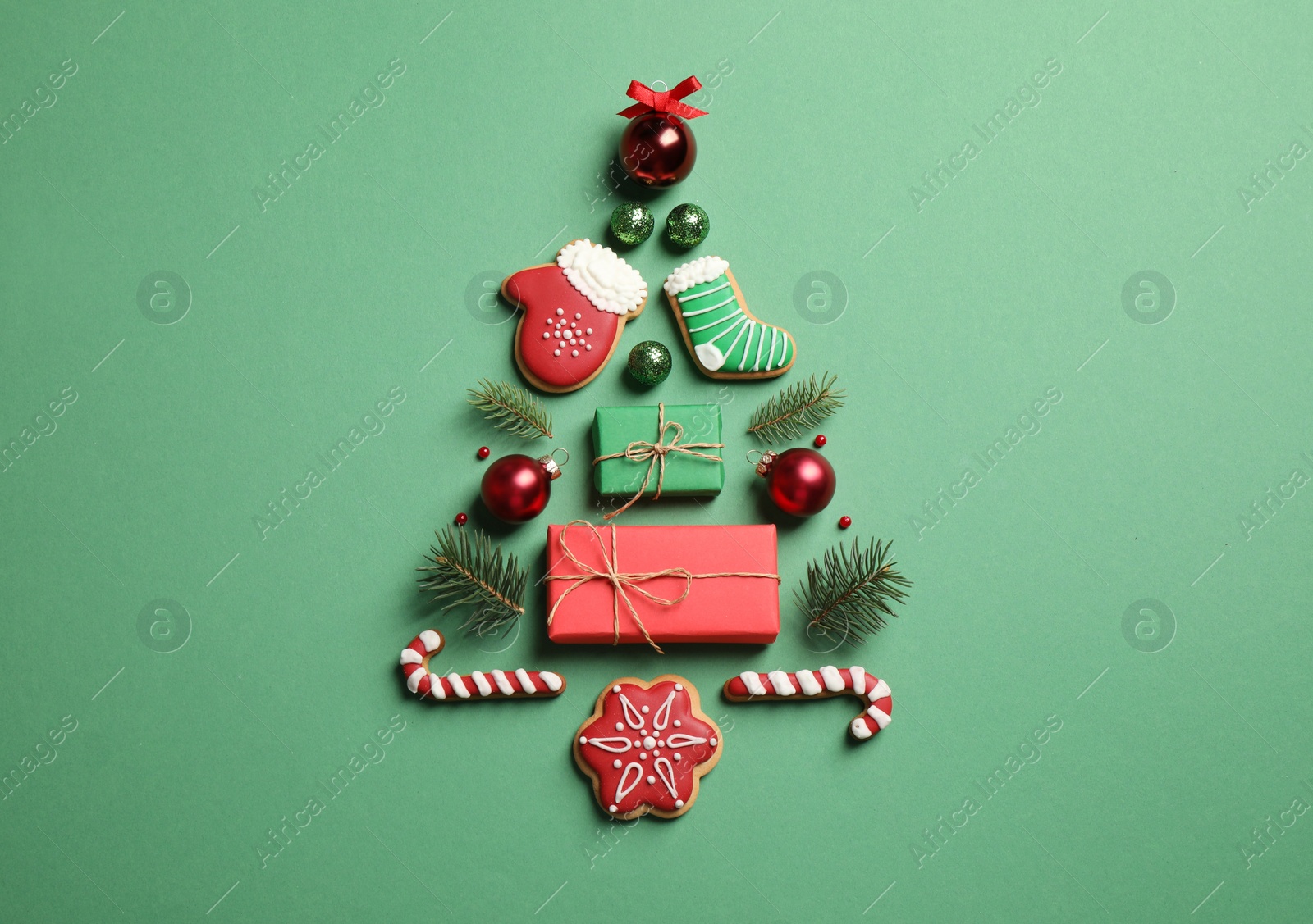 Photo of Christmas tree silhouette of fir branches and festive decoration on green background, flat lay