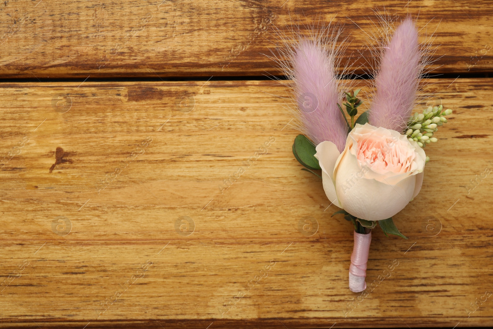 Photo of Small stylish boutonniere on wooden table, top view. Space for text