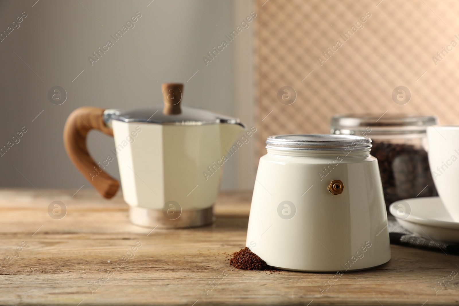 Photo of Moka pot and ground coffee on wooden table indoors. Space for text