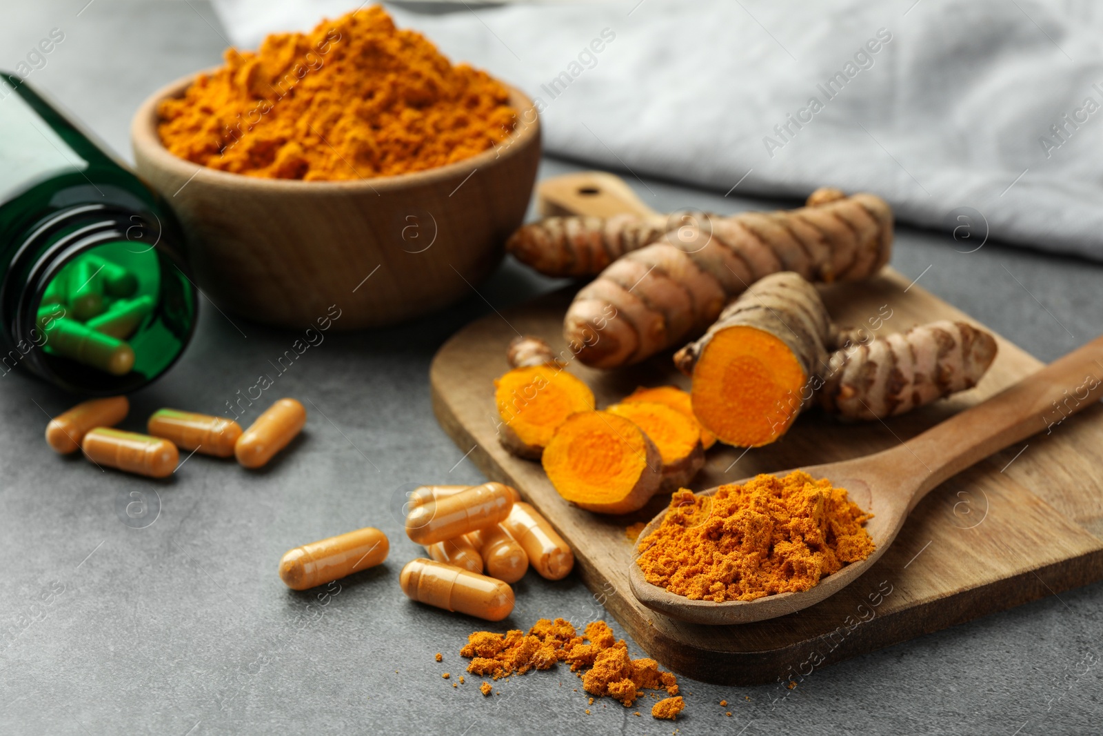 Photo of Aromatic turmeric powder, pills and raw roots on grey table. Space for text