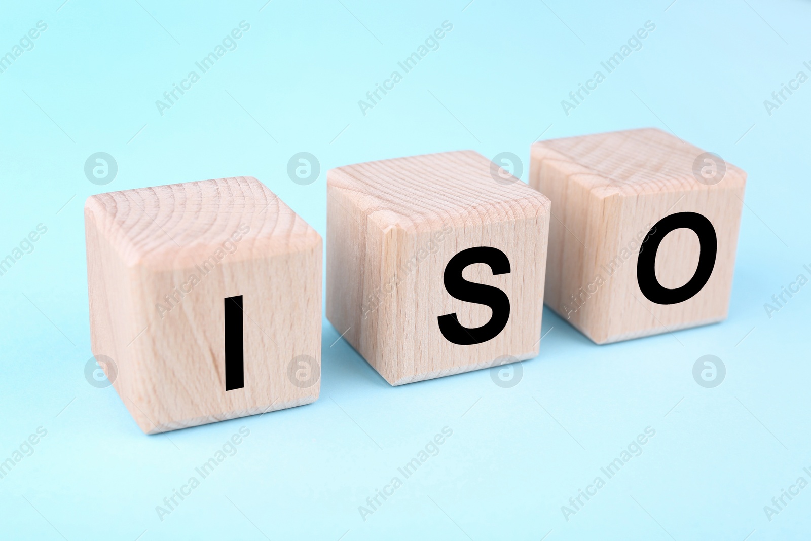 Photo of International Organization for Standardization. Wooden cubes with abbreviation ISO on light blue background, closeup