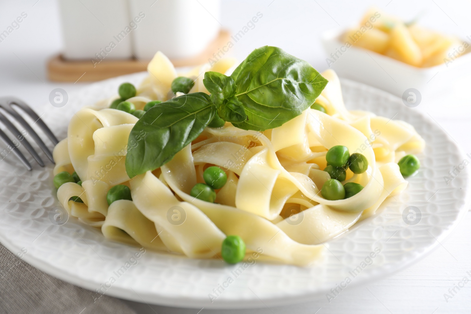 Photo of Delicious pasta with green peas served on white table, closeup