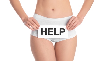 Photo of Young woman holding paper with word HELP near underwear on white background. Gynecology