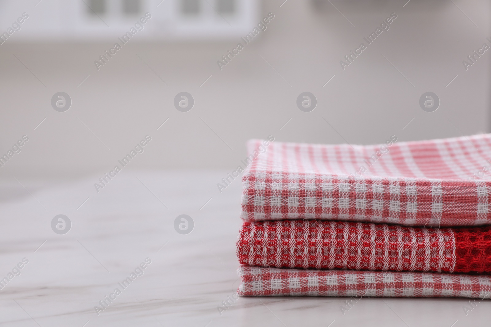 Photo of Stack of kitchen towels on white marble table. Space for text