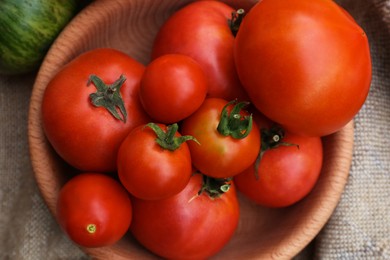 Many different ripe tomatoes in bowl on table, top view