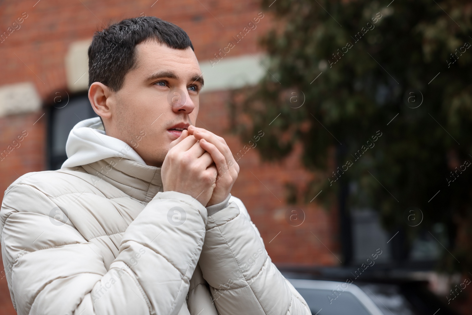 Photo of Sick young man coughing on city street. Cold symptoms