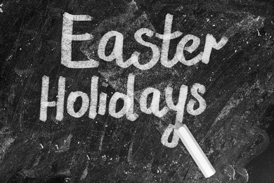 Image of Text Easter Holidays and chalk on blackboard, top view. School break 