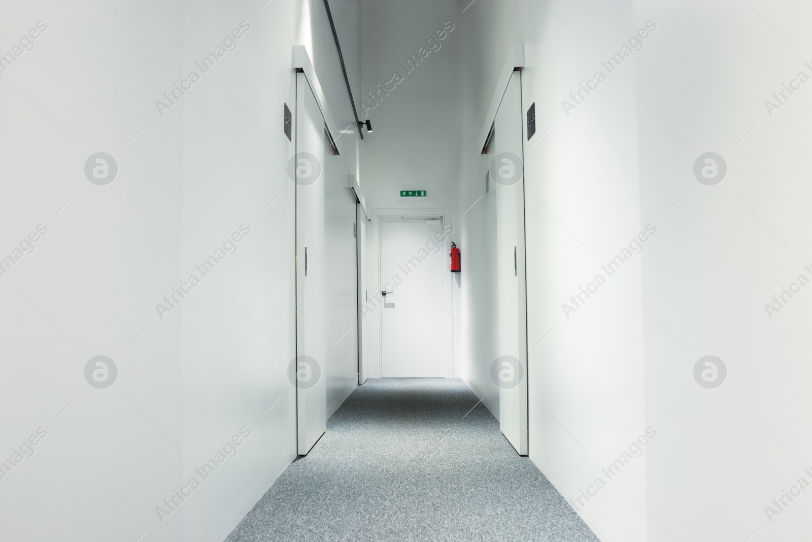 Photo of Narrow white hallway in hostel. Modern design