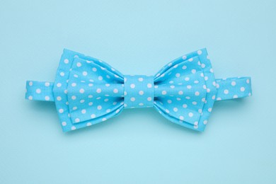 Photo of Stylish light blue bow tie with polka dot pattern on color background, top view