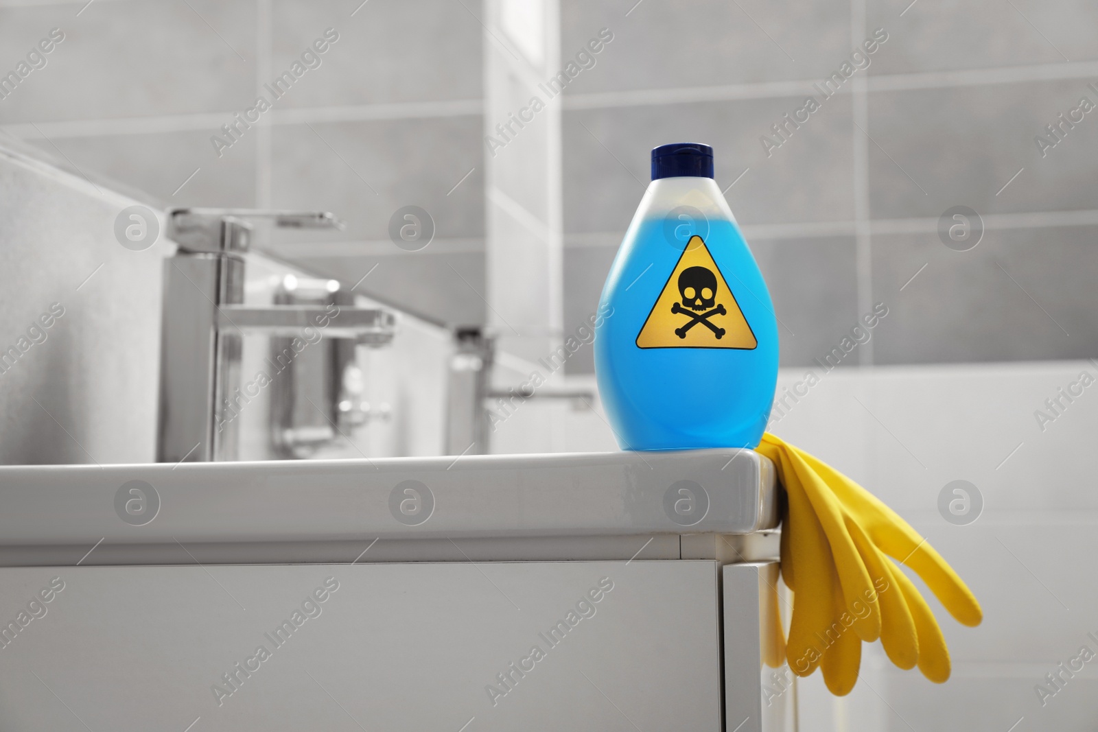 Photo of Bottle of toxic household chemical with warning sign and gloves in bathroom, space for text