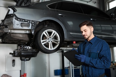 Photo of Technician checking car on hydraulic lift at automobile repair shop