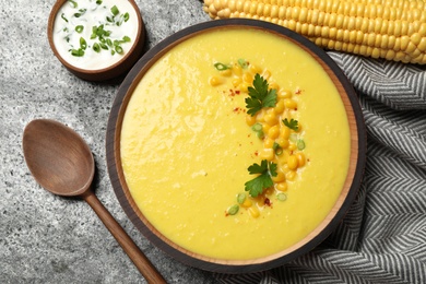 Photo of Delicious creamy corn soup served on grey table, flat lay