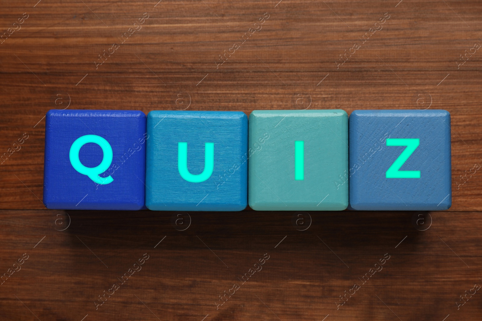 Photo of Blue cubes with word Quiz on wooden table, flat lay