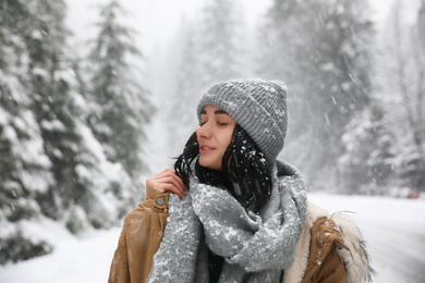 Photo of Young woman wearing warm clothes outdoors on snowy day. Winter vacation