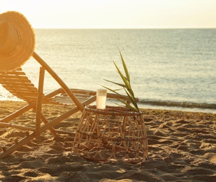 Wooden deck chair and wicker table with drink near sea. Summer vacation