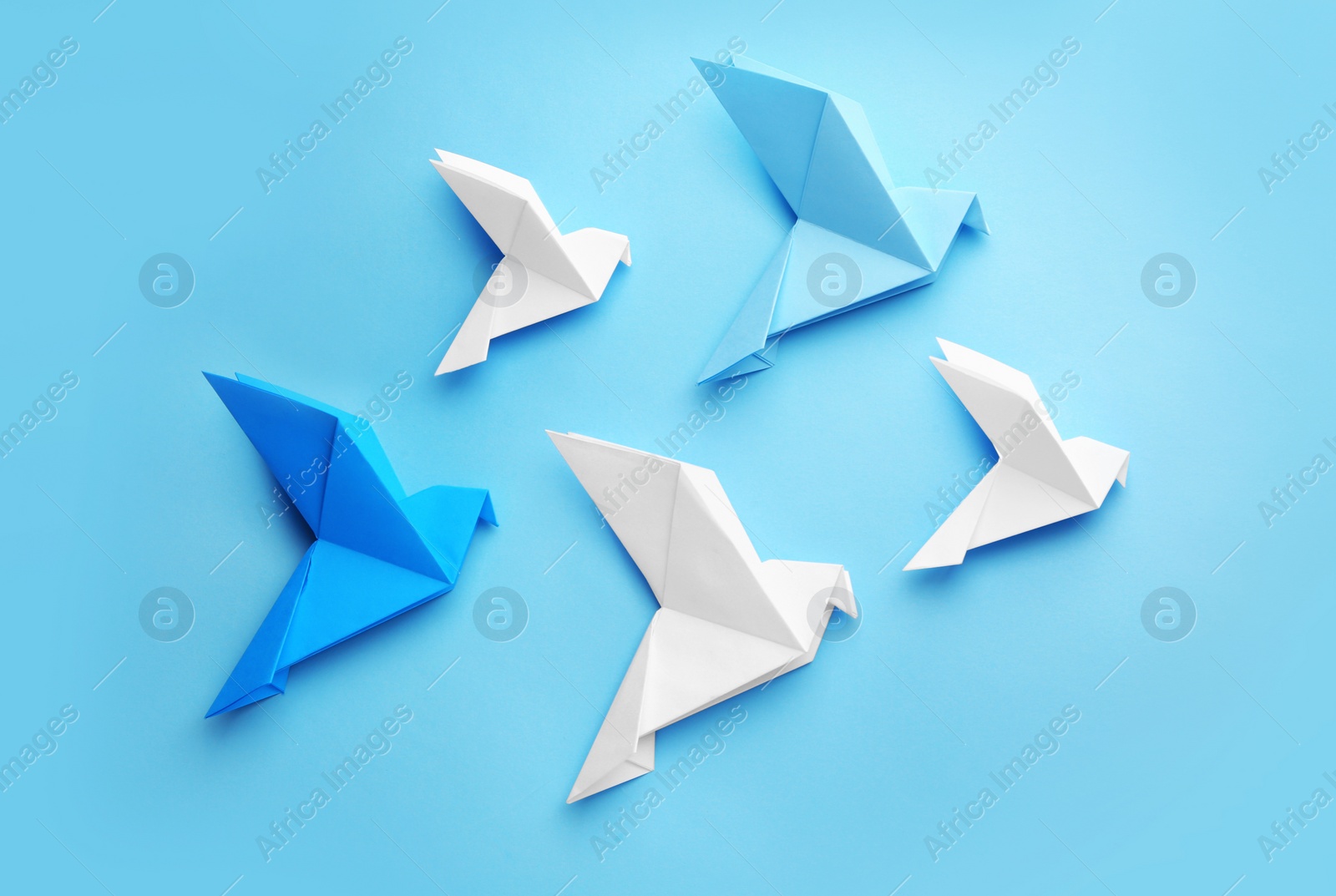 Photo of Origami art. Colorful handmade paper birds on light blue background, flat lay