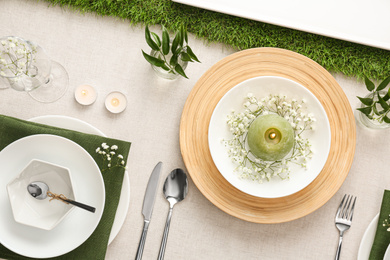 Elegant table setting with green plants on light cloth, flat lay