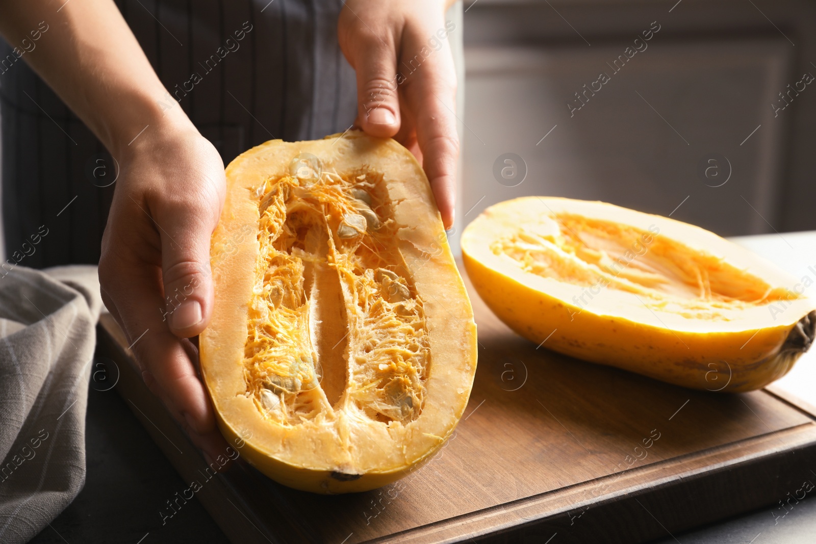 Photo of Woman holding cut spaghetti squash on table, closeup