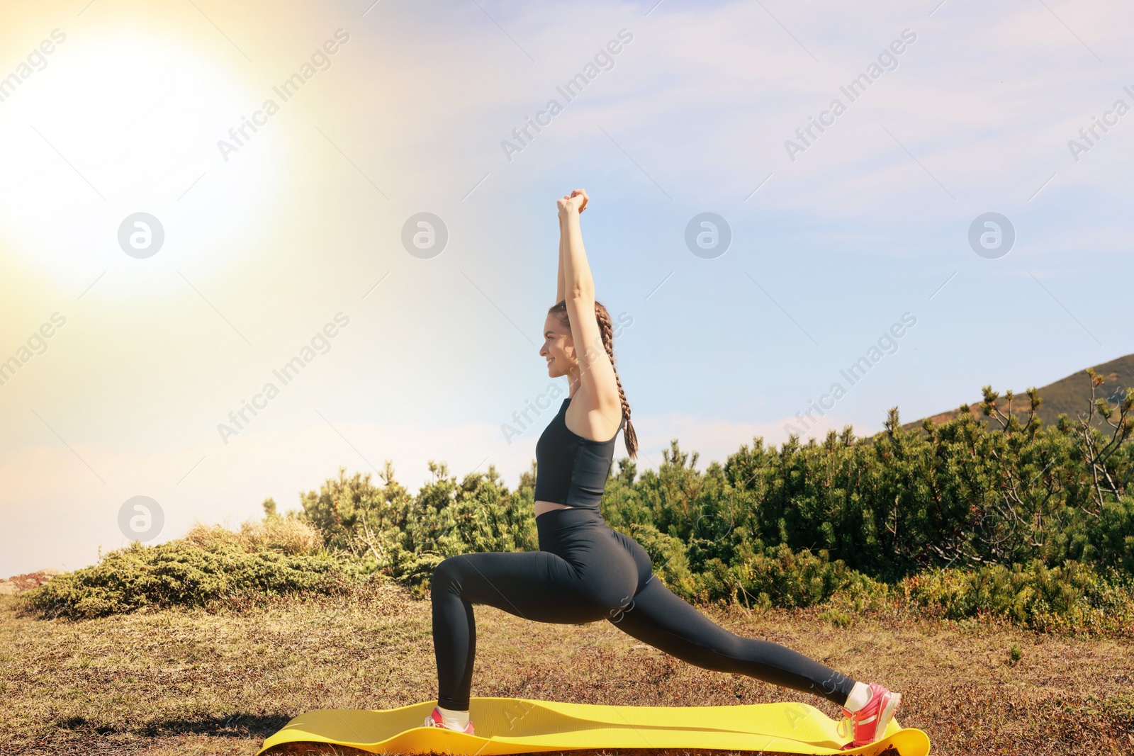 Image of Beautiful young woman doing yoga in mountains on sunny morning