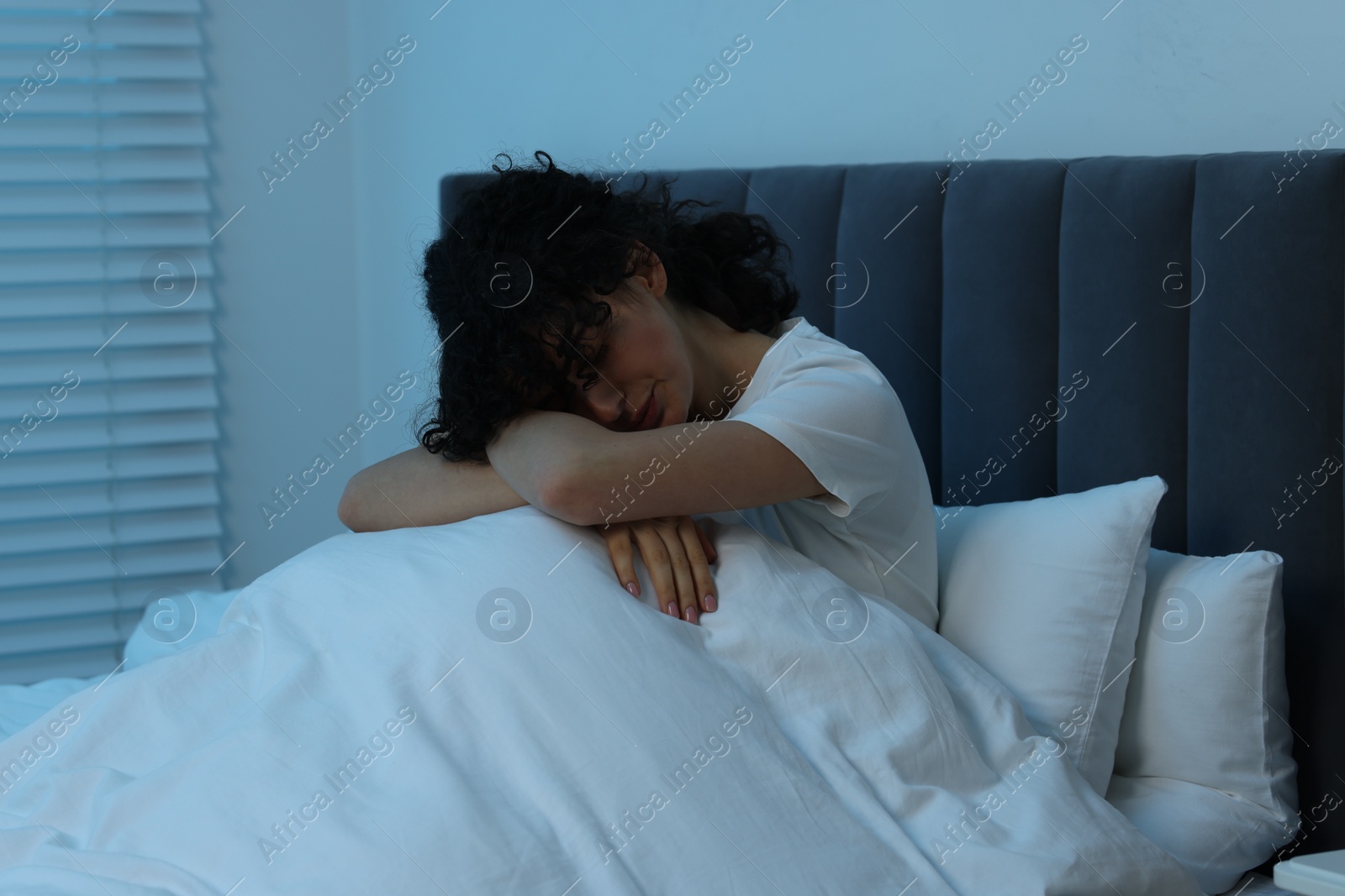 Photo of Young woman suffering from headache in bed at night